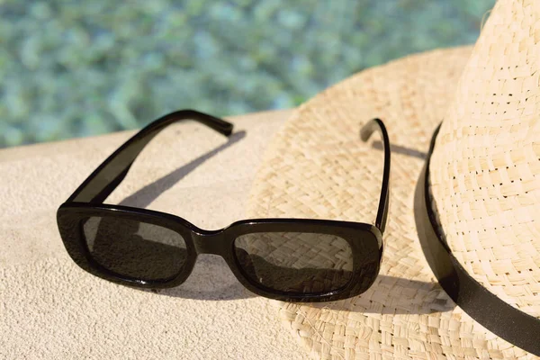 Stylový Klobouk Sluneční Brýle Blízkosti Venkovního Bazénu Slunečného Dne Detailní — Stock fotografie
