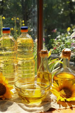 Organic sunflower oil and flowers on window sill indoors