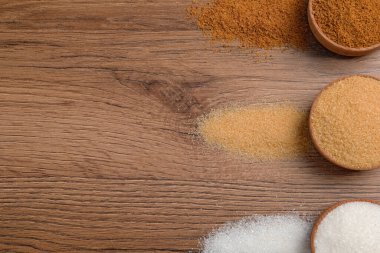 Tahta masanın üzerinde farklı şekillerde granüle şeker var. Metin için boşluk