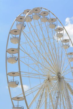 Mavi bulutlu gökyüzüne karşı büyük beyaz gözlem çarkı, düşük açı