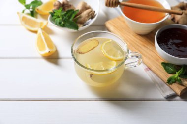 Lezzetli zencefilli çay ve malzemeler beyaz ahşap masada.