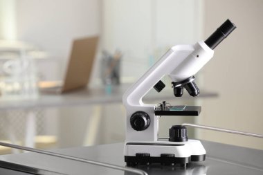 Modern medical microscope on metal table in laboratory, space for text