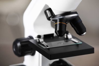 Bulanık arka planda cam kaydıraklı modern tıbbi mikroskop, yakın plan. Laboratuvar ekipmanları