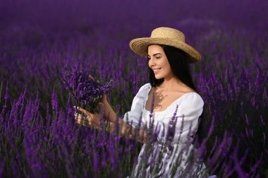 Beautiful young woman with bouquet in lavender field