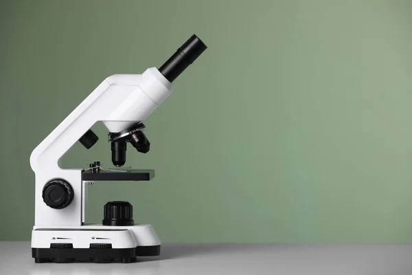 緑の背景を背景にテーブルの上の近代的な顕微鏡 テキストのスペース — ストック写真