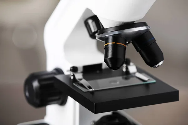 Modern medical microscope with glass slide on blurred background, closeup. Laboratory equipment