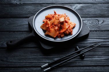 Siyah ahşap masada servis edilen Çin lahanalı nefis kimchi.