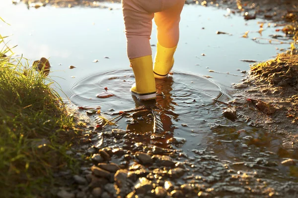小さな女の子は 屋外の水たまりの中を歩いてゴム製のブーツを着て クローズアップ — ストック写真