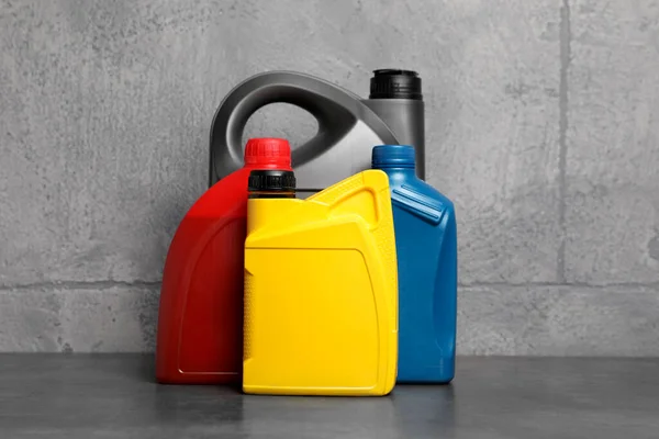 stock image Motor oil in different canisters on table near grey wall