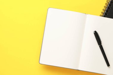 Not defterleri ve kalem sarı arka plan, üst görünüm. Metin için alan
