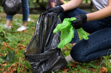 Plastik çantalı kadın parkta çöp topluyor, yakın plan.
