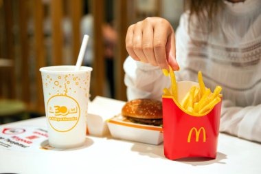 SAVAŞ, POLAND - SEPTEMBER 04, 2022: Kafedeki masada McDonald 's patates kızartması, burger ve içecek yiyen kadın, yakın plan