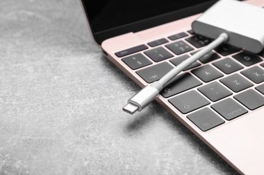 C tipi konnektör ve dizüstü bilgisayarı olan USB kablosu gri masada, yakın plan. Metin için boşluk