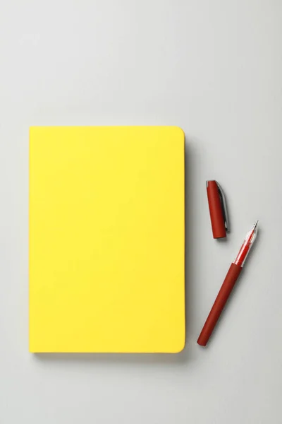 stock image Yellow notebook and pen on gray background, flat lay