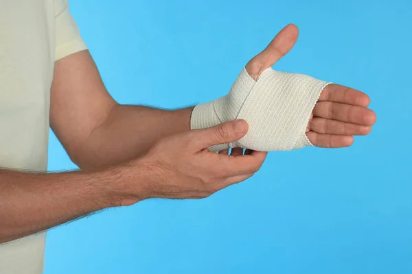 Homem Com Mão Embrulhada Bandagem Médica Fundo Azul Claro Close — Fotografia de Stock