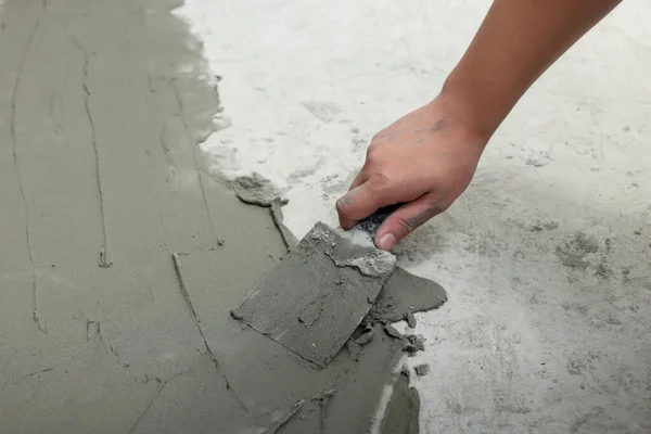 stock image Worker with spatula applying adhesive mix for tiles on floor, closeup