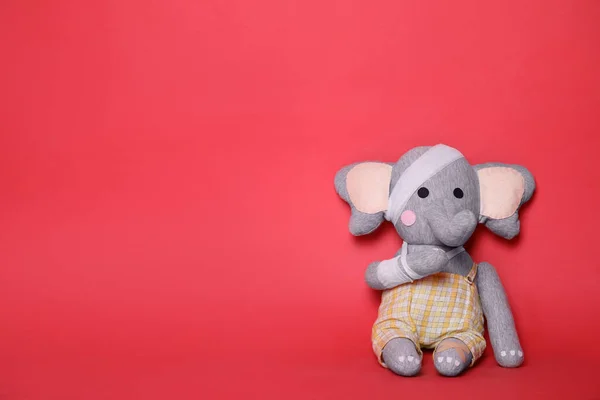 Gajah Mainan Dengan Perban Latar Belakang Merah Ruang Untuk Teks — Stok Foto