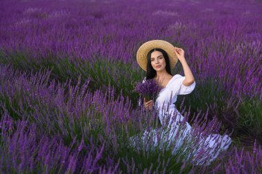 Beautiful young woman sitting in lavender field