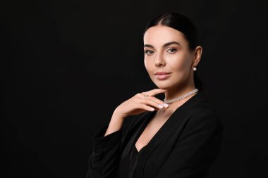 Siyah arka planda zarif inci takıları olan genç bir kadın, metin için yer var.