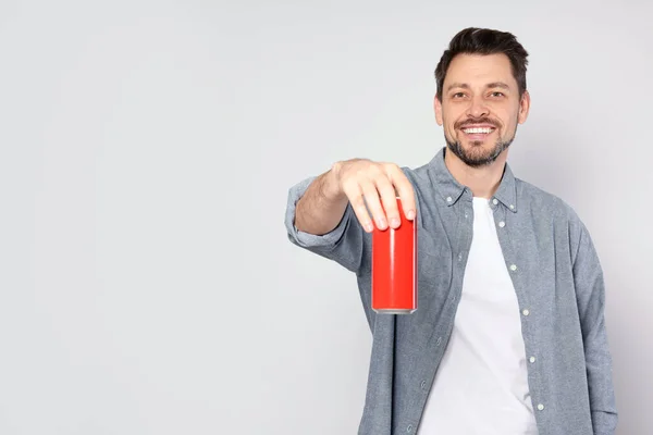 Ευτυχισμένος Άνθρωπος Κρατώντας Κόκκινο Τενεκεδάκι Ποτό Ανοιχτό Γκρι Φόντο Χώρος — Φωτογραφία Αρχείου