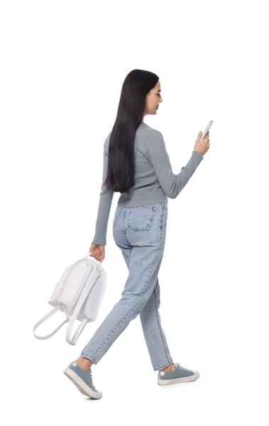 年轻女子在白色背景下走路时使用智能手机 — 图库照片
