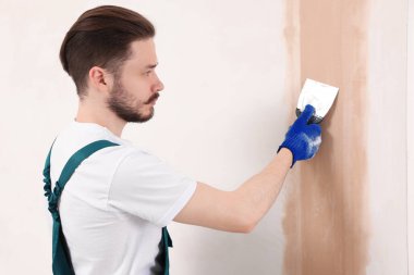Üniformalı işçiler duvarları sıva ile kaplıyor.