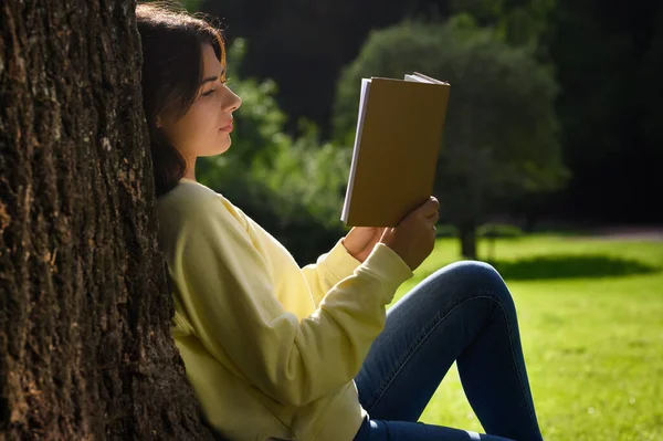 Ung Kvinna Läser Bok Nära Träd Parken Solig Dag — Stockfoto