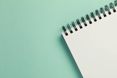Blank notebook on turquoise background, top view. Space for text