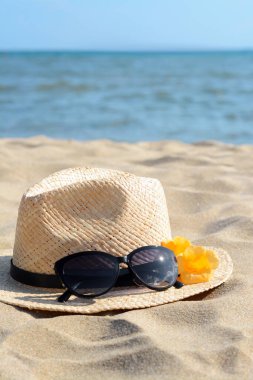 Güzel güneş gözlüklü şapka ve deniz kenarında kumdaki çiçekler. Metin için boşluk
