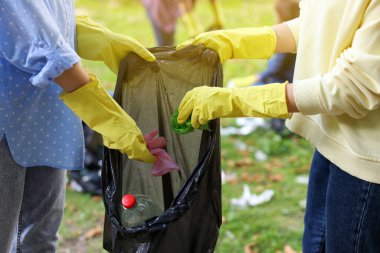 Plastik çantalı kadınlar parkta çöp topluyor, yakın plan.