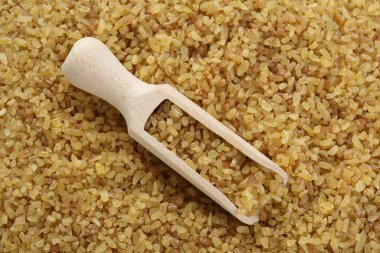 Tahta kepçeyle mısır gevreği pişmemiş bulgur, üst manzara.