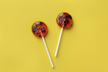 Tatlı renkli lolipoplar, sarı arka planda böğürtlenler, düz uzanmış