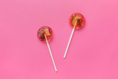 Sweet colorful lollipops with berries on pink background, flat lay
