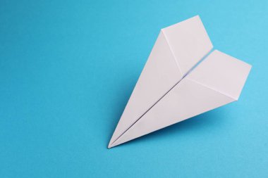 Açık mavi zemin üzerinde el yapımı beyaz kağıt uçak, metin için boşluk