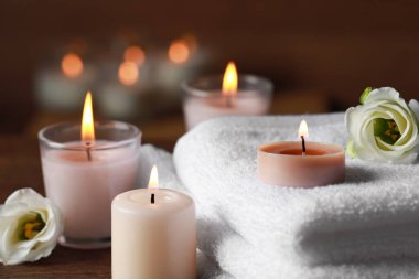 Güzel bir spa kompozisyonu, yanan mumlar ve ahşap masa üzerinde çiçekler, yakın plan.