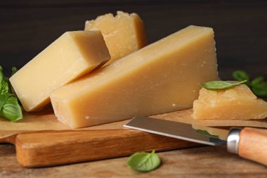 Ahşap masada fesleğen ve bıçaklı nefis parmesan peyniri, yakın plan.