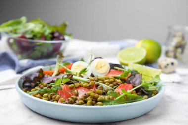 Bir tabak salata ve beyaz mermer masada fasulye.