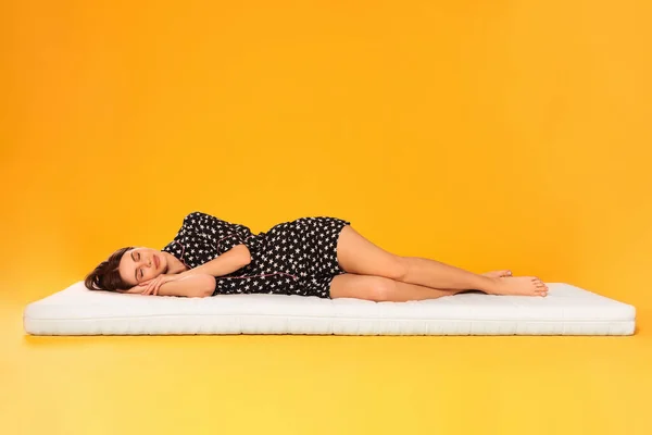 Mujer Joven Durmiendo Colchón Suave Sobre Fondo Naranja — Foto de Stock