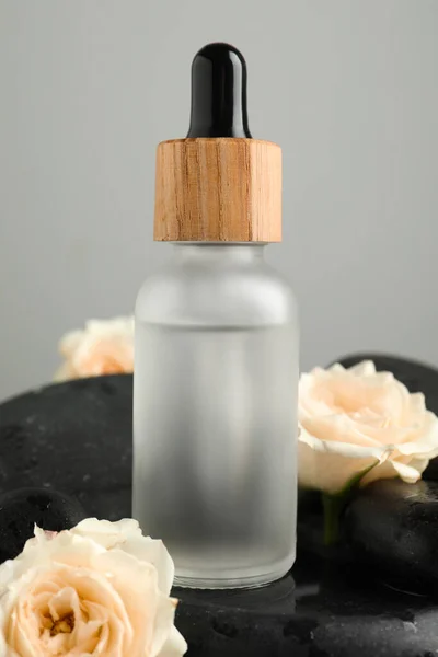 Bottle Face Serum Beautiful Roses Spa Stones Grey Background Closeup — Stock Photo, Image