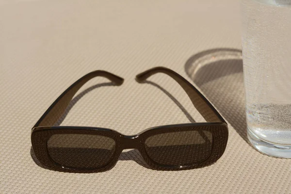 Stylové Sluneční Brýle Sklenice Vody Šedém Povrchu Detailní Záběr — Stock fotografie