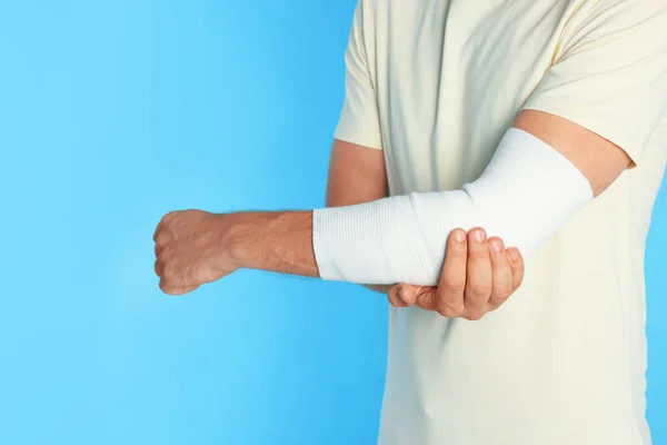 Man Med Arm Insvept Medicinskt Bandage Ljusblå Bakgrund Närbild — Stockfoto