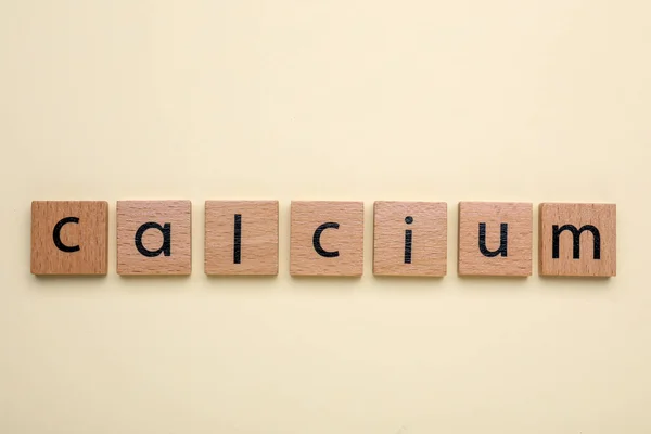 stock image Word Calcium made of wooden cubes with letters on beige background, top view