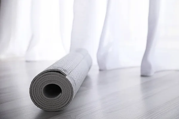 stock image Rolled karemat or fitness mat on wooden floor. Space for text