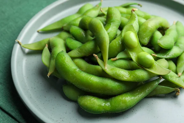 Plate of green edamame beans in pods on table, closeup