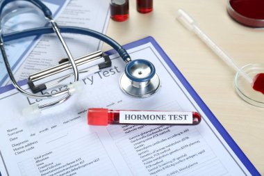 Hormon testi. Üzerinde kan, steteskop ve laboratuvar formu olan örnek tüp.