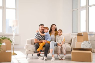 Mutlu bir aile yeni dairede koltukta oturuyor. Taşınma günü