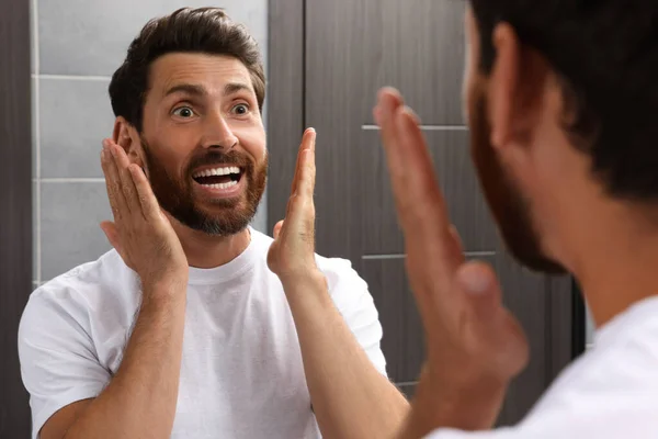 Tunteellinen Parrakas Mies Katselee Peiliä Kylpyhuoneessa — kuvapankkivalokuva