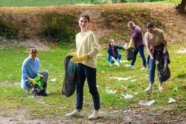 stock image Group of people with plastic bags collecting garbage in park
