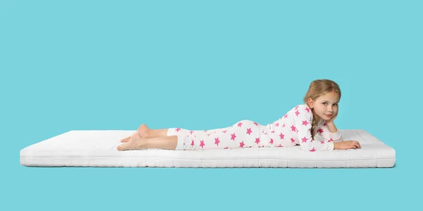 小女孩躺在舒适的床垫上 衬托着浅蓝色的背景 文字的空间 — 图库照片