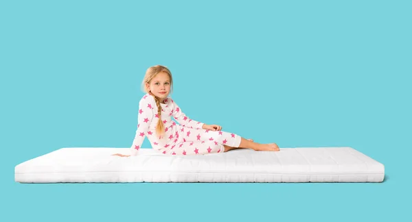 Kleines Mädchen Auf Matratze Vor Hellblauem Hintergrund — Stockfoto